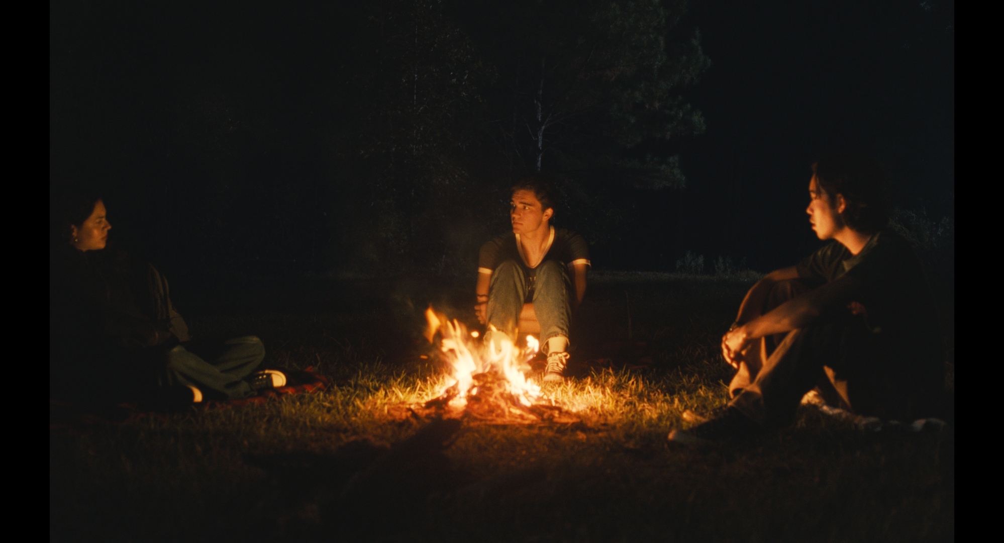 Three characters sitting around a campfire